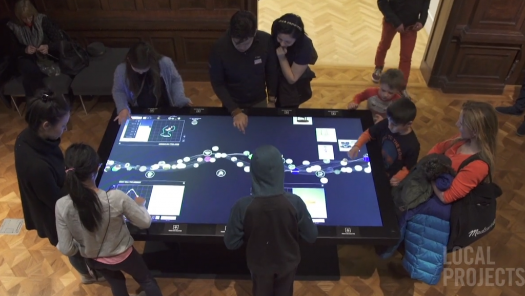 Still frame from video produced by Local Projects showing social use of interactive tables.