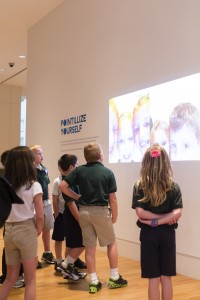 Visitors observe projected self-portraits created using the Pointillize Yourself app, outside the exhibition